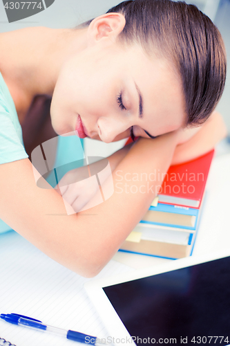 Image of tired student sleeping on stock of books