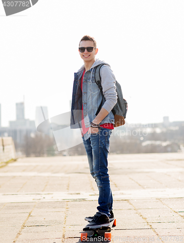 Image of happy young man or teenage boy riding on longboard