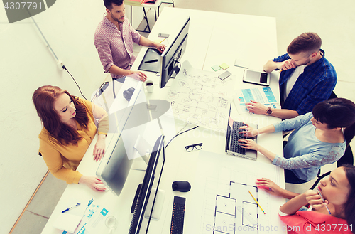 Image of creative team with computers, blueprint at office