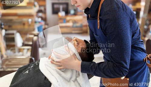 Image of barber softening male face sking with hot towel