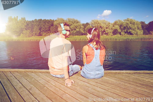 Image of teenage couple with headphones on river berth