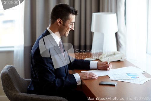 Image of businessman with papers working at hotel room