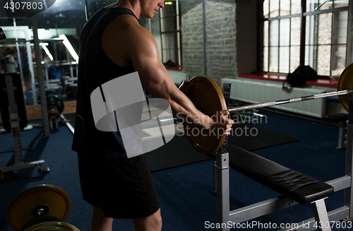 Image of man attaching weight to barbell in gym