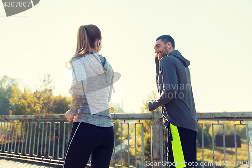 Image of happy couple with earphones running outdoors