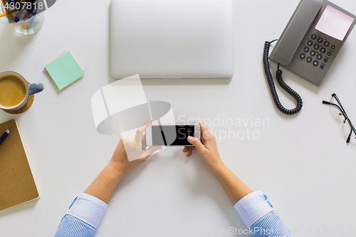 Image of businesswoman with smartphone working at office