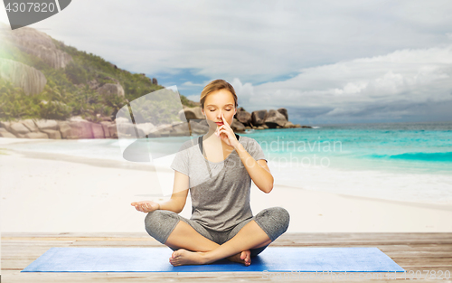 Image of woman doing yoga breathing exercise on beach