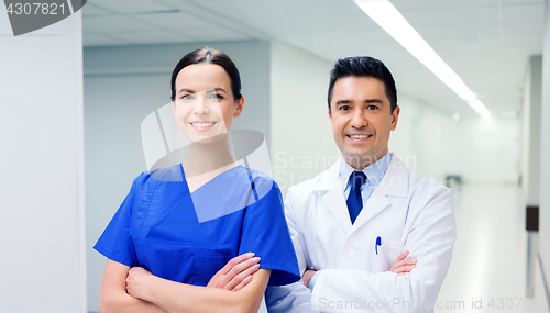 Image of smiling doctor in white coat and nurse at hospital