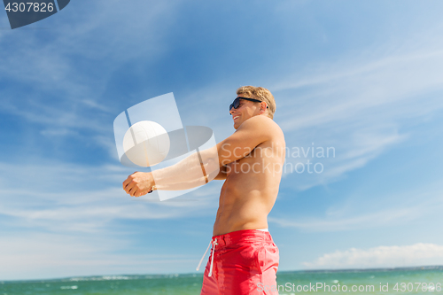 Image of young man with ball playing volleyball on beach