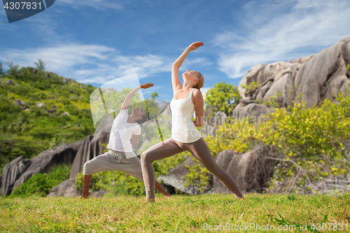 Image of couple doing yoga exercises on beach