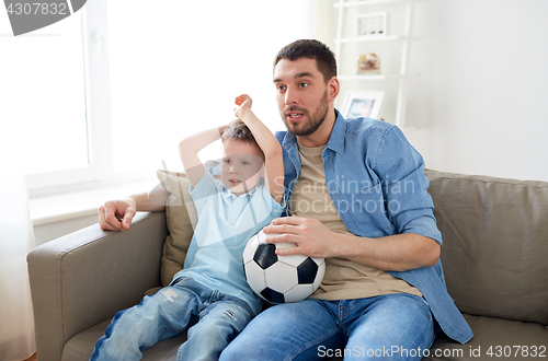 Image of father and son watching soccer on tv at home