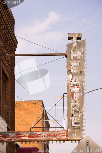 Image of Old Vertical composition metal neon theatre sign against blue sk