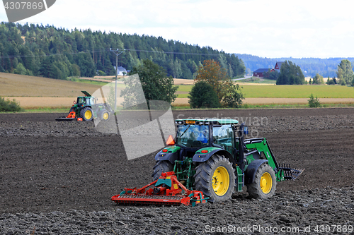 Image of Two John Deere Tractors Cultivating Field
