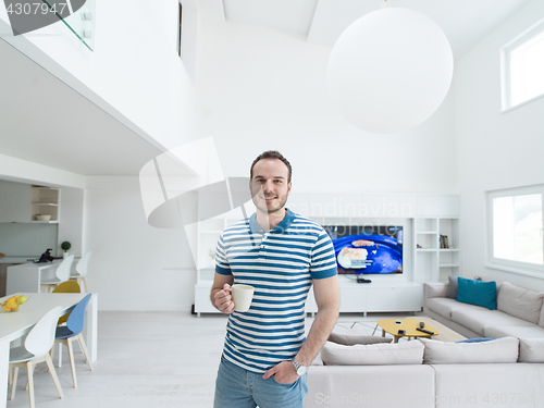 Image of young man drinking morning coffee by the window