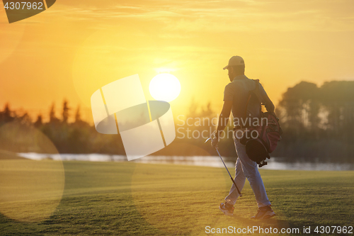 Image of handsome middle eastern golfer carrying bag and walking to next 