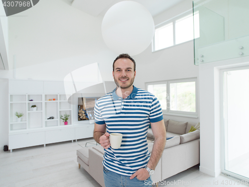 Image of young man drinking morning coffee by the window