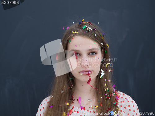 Image of woman blowing confetti in the air isolated over gray