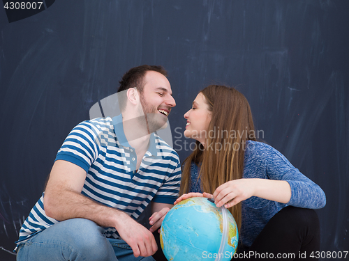 Image of couple in casual clothing investigating globe