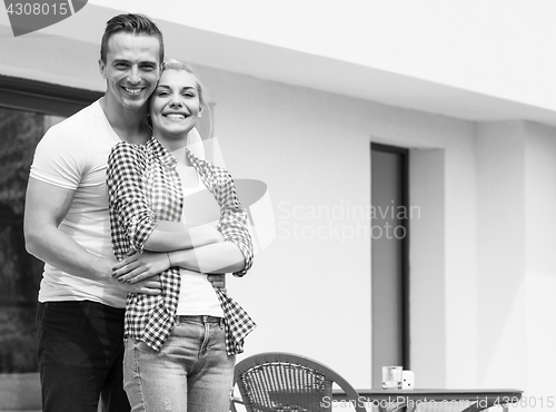 Image of Happy two young lovers standing in front of modern house