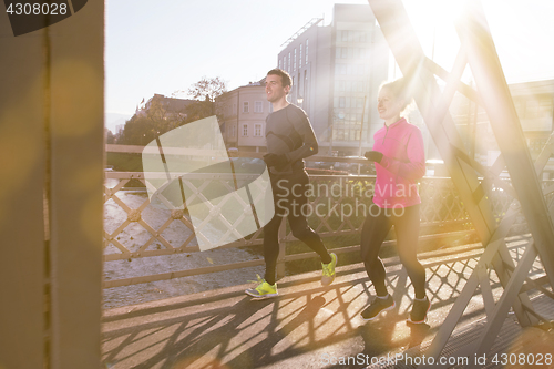 Image of healthy young couple jogging in the city