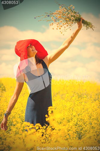 Image of joyful woman in a red hat with a bouquet of wild flowers