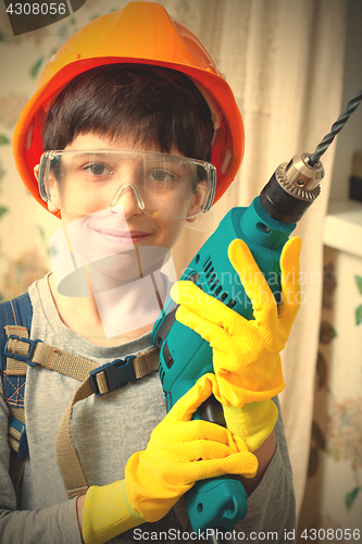 Image of boy builder in goggles and with a drill