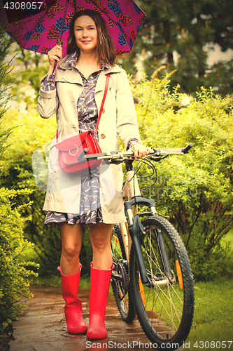 Image of woman with an umbrella and a bicycle on a rainy day