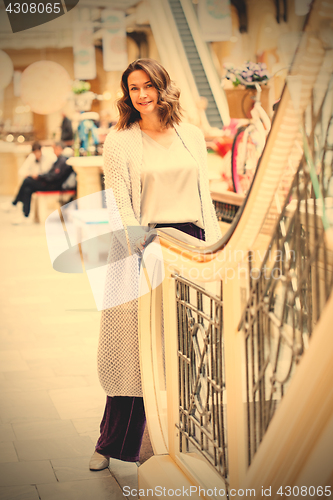 Image of woman in a blue knitted coat near an escalator in a shopping cen