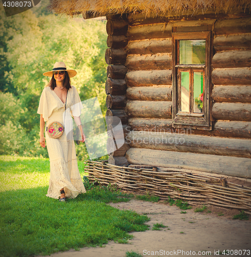 Image of Cheerful smiling woman in a white dress and a straw