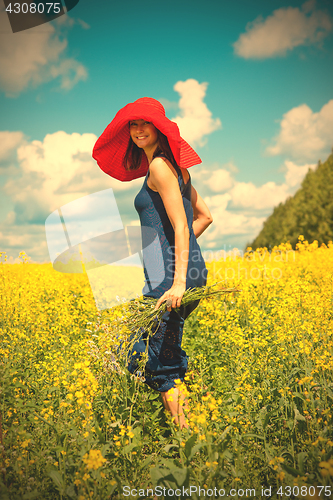 Image of happy woman in a red hat with a bouquet of wildflowers