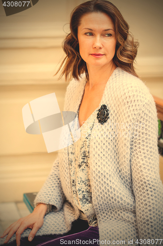 Image of beautiful middle-aged woman in a blue knitted jacket with a broo