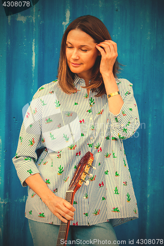 Image of Portrait of a beautiful smiling woman with a guitar 