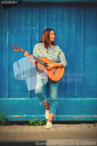 Image of Beautiful smiling woman in jeans playing guitar 