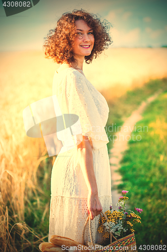 Image of beautiful woman in a white dress with a basket with bread and mi