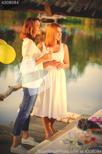 Image of two young beautiful women at a party near the water