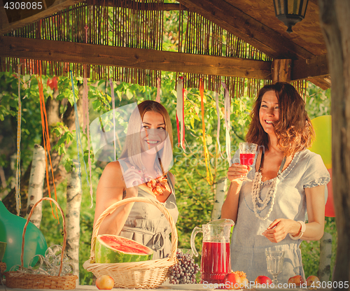 Image of laughing women near a festive table with a wine glass in hands