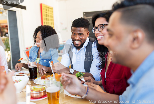 Image of happy friends eating and talking at restaurant