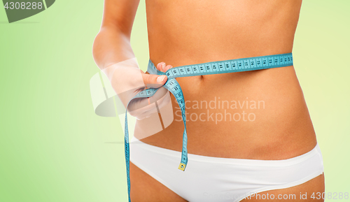 Image of close up of woman body with measure tape on waist