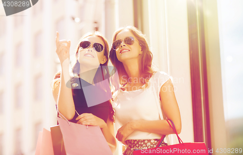 Image of happy women with shopping bags outdoors