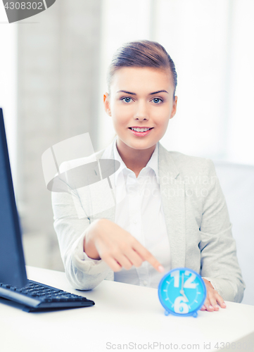 Image of attractive businesswoman pointing at clock