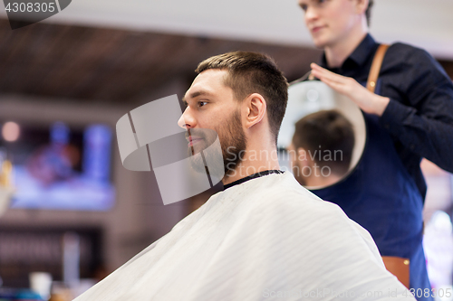 Image of man and hairdresser with mirror at barbershop