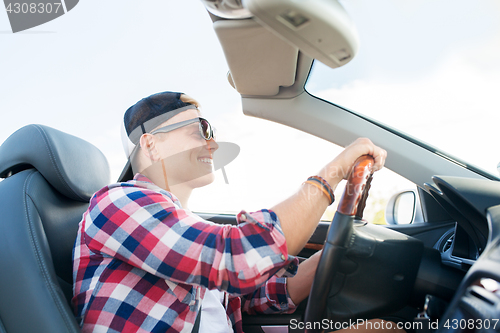 Image of happy young man driving convertible car