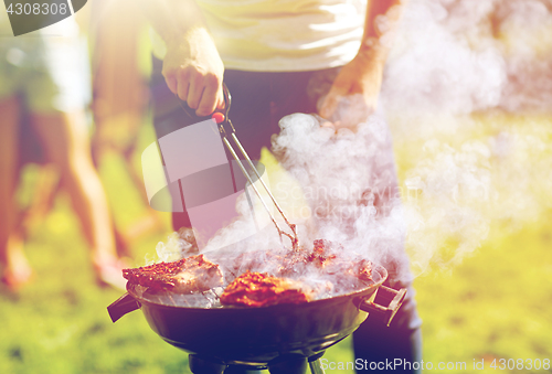 Image of man cooking meat on barbecue grill at summer party