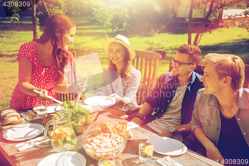 Image of happy friends having dinner at summer garden party