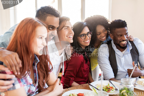 Image of happy friends eating at restaurant