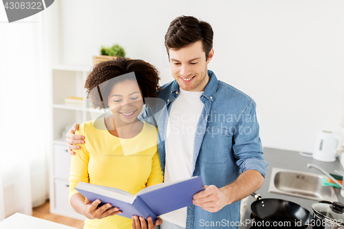 Image of happy couple with cooking book at home kitchen