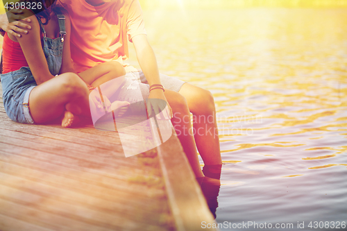 Image of happy teenage couple sitting on river berth