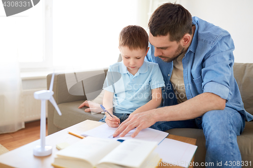 Image of father and son with toy wind turbine at home