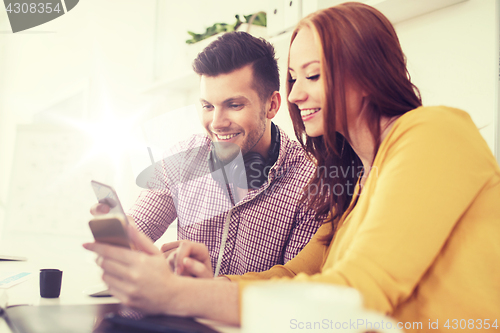 Image of happy creative team with smartphones at office