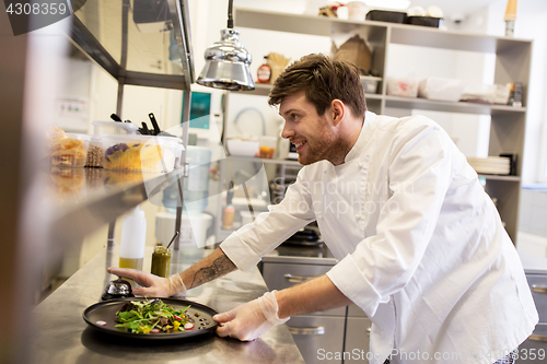 Image of happy male chef cooking food at restaurant kitchen