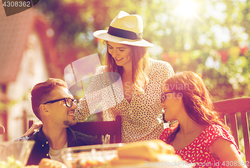 Image of happy friends having dinner at summer garden party